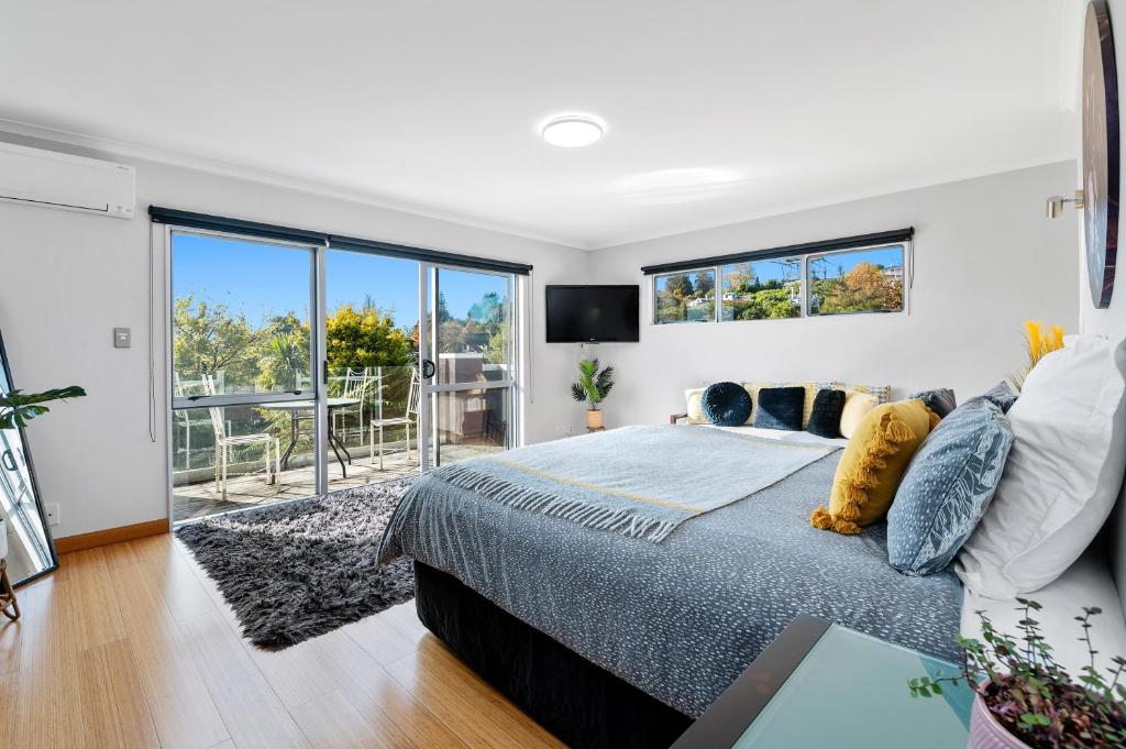 a bedroom with a bed and a large window at Zodiac Bay Lake Retreat in Rotorua
