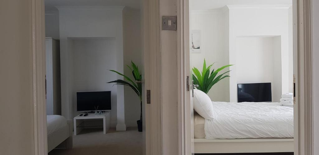 a white bedroom with a bed and a tv at Mirandas Place in Gillingham