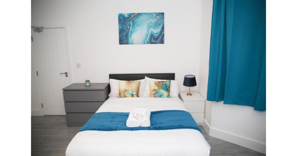a bedroom with a large bed with blue curtains at Cricklewood Deluxe Ensuite Room in London