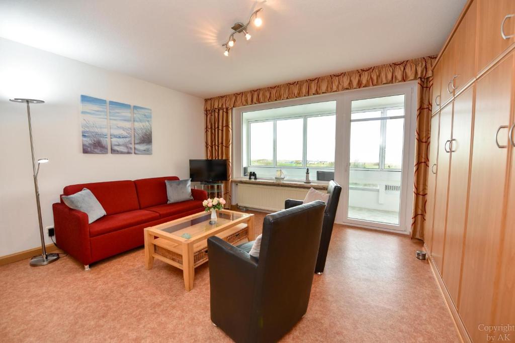 sala de estar con sofá rojo y mesa en Haus "Atlantic" Appartement ATL303, en Cuxhaven