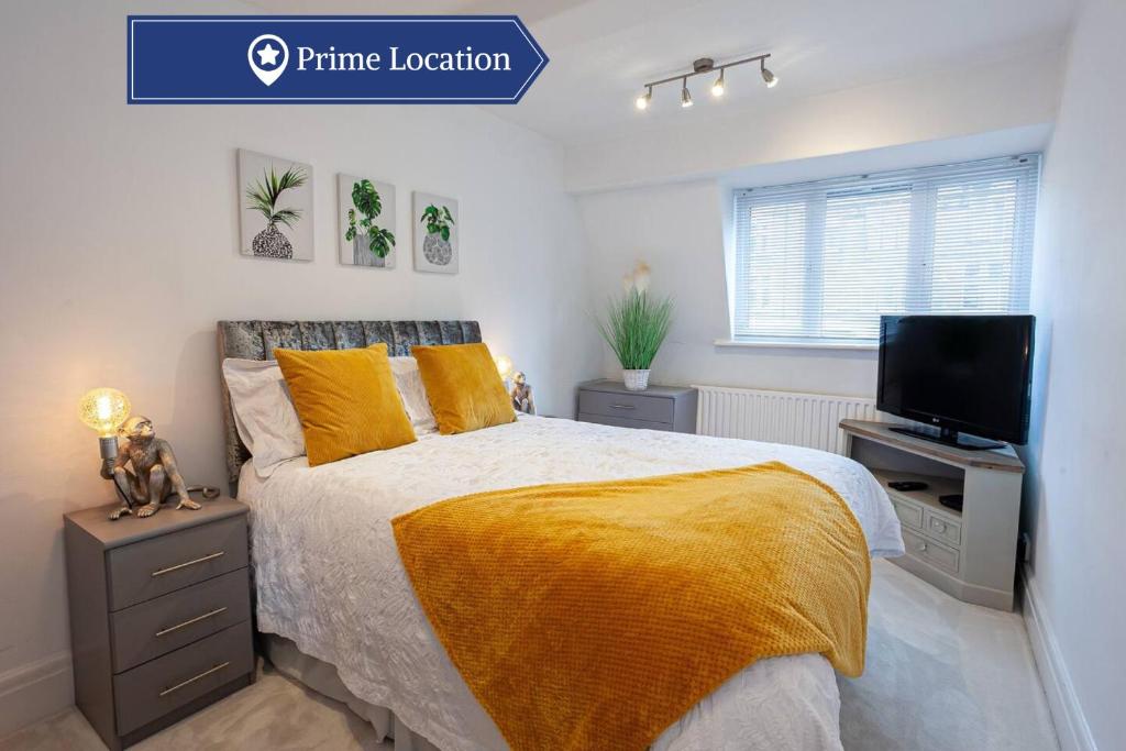 een slaapkamer met een bed met een gele deken en een televisie bij Cosy 2 Bed Apartment - Close to Leeds Centre in Moortown