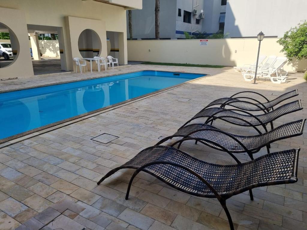 une piscine avec deux bancs en face d'un bâtiment dans l'établissement Apartamento 50 metros do Mar da Brava Floripa, à Florianópolis
