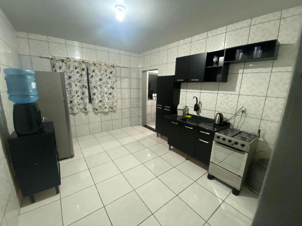 a kitchen with black cabinets and white tile floors at Apartamento no centro com suíte in Ametista do Sul