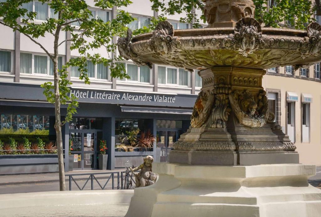 una estatua de una fuente frente a un edificio en Hotel Litteraire Alexandre Vialatte, BW Signature Collection, en Clermont-Ferrand