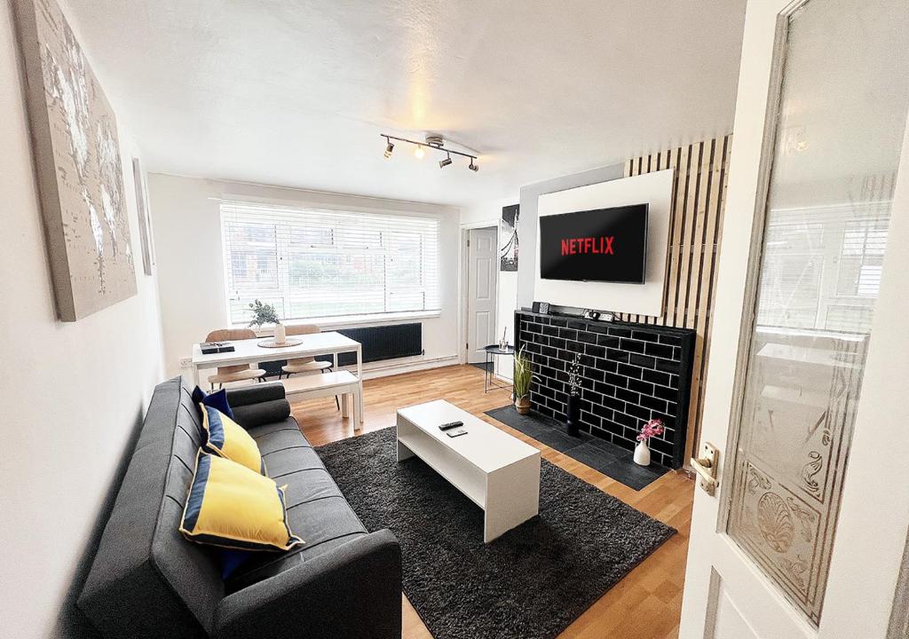 uma sala de estar com um sofá preto e uma televisão em Beautiful Modern Apt (Sleeps 5) em Croydon