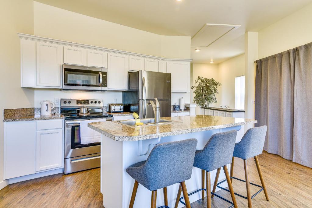 a kitchen with white cabinets and a island with bar stools at Portland Apartment about 1 Mi to Downtown! in Portland