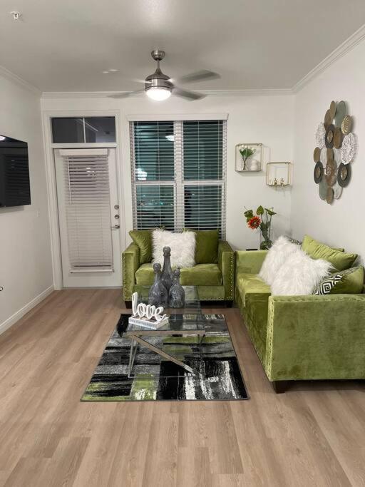 sala de estar con sofá verde y mesa en Midtown Getaway en Houston