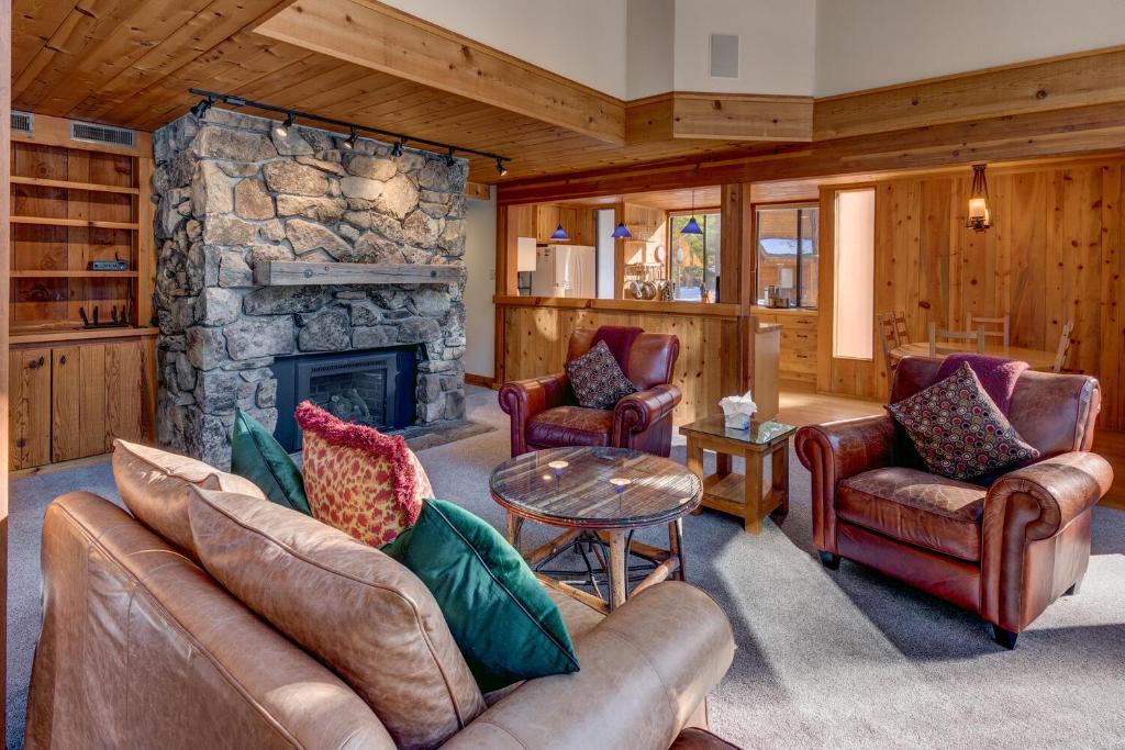 sala de estar con muebles de cuero y chimenea de piedra. en Snowbird Retreat at Northstar - Beautiful 4BR with Private Hot Tub, Free Ski Shuttle, HOA Amenities, en Truckee