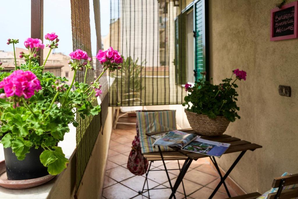 パレルモにあるAttico Finocchiaro - Terrazza in Centro Wifi Freeの鉢植えの植物2本とテーブル付きのバルコニー