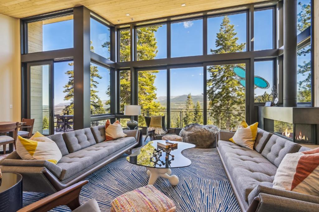 una sala de estar con grandes ventanas y sofás en Soaring Peak at Northstar- Endless Views at this Deluxe Ski-in Ski-out Northstar Residence en Truckee