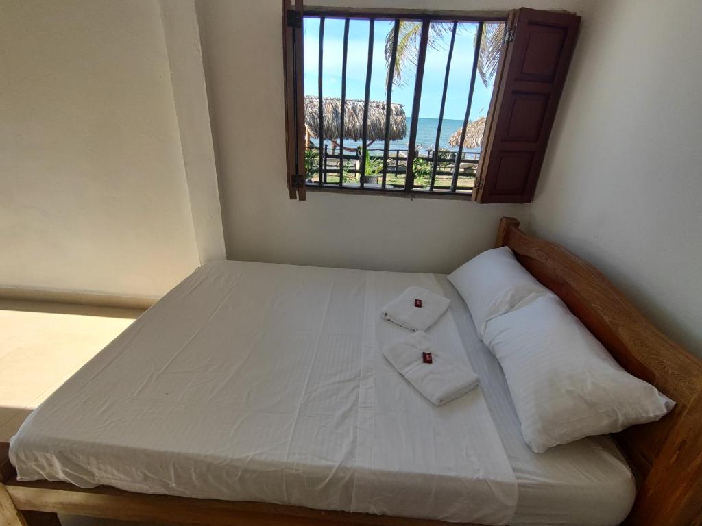 Cette chambre comprend un lit avec deux oreillers et une fenêtre. dans l'établissement La casa del mar, à San Bernardo del Viento