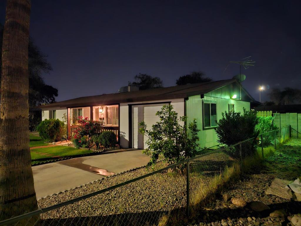 a green house with a fence in front of it at Chandler Charming Home in Chandler