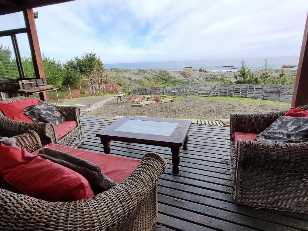 patio con sillas de mimbre, mesa y vistas en Casa Curanipe, en Curanipe