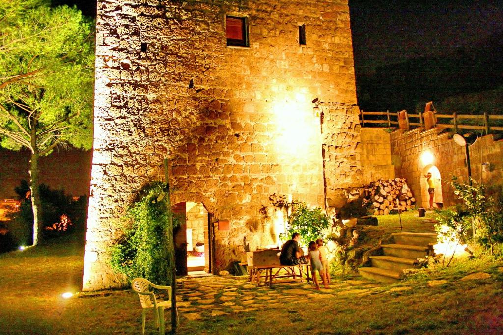 two people sitting on a bench outside of a building at night at Country House La Torre in Tuscania