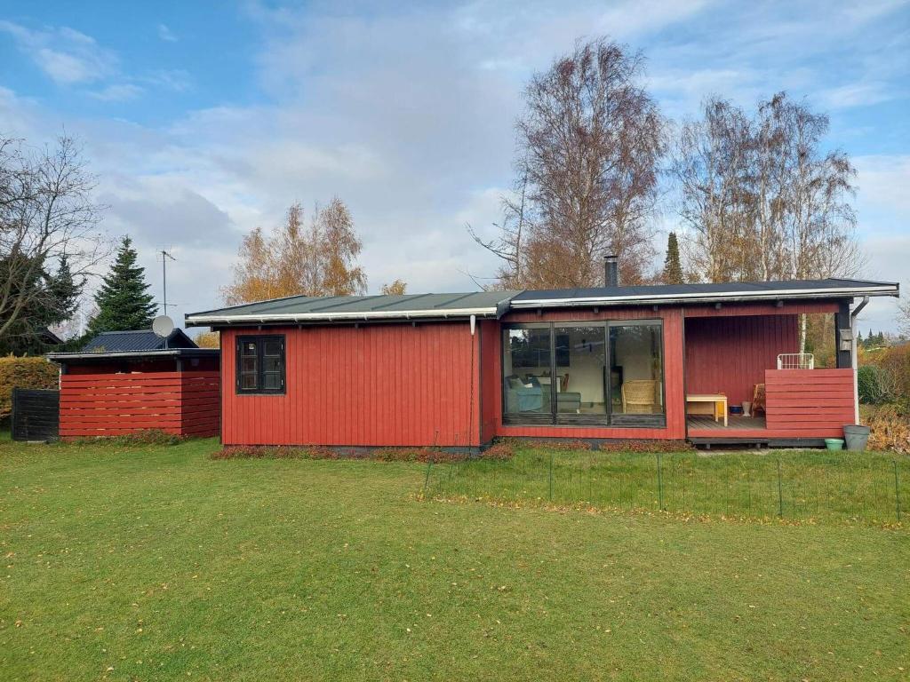 een rood huis met een groot raam in een tuin bij Holiday home Væggerløse XL in Bøtø By