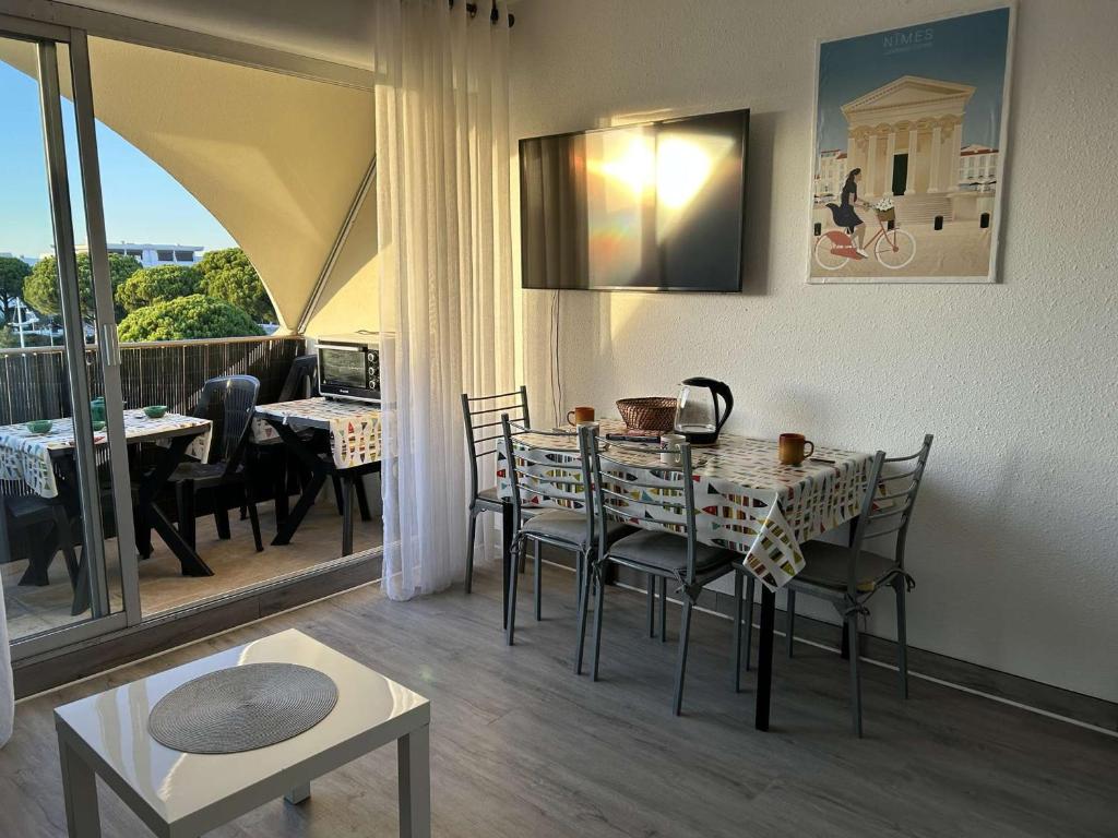 une salle à manger avec une table et des chaises et un balcon dans l'établissement Studio cabine climatisé avec piscine, Port Camargue - FR-1-250-262, au Grau-du-Roi