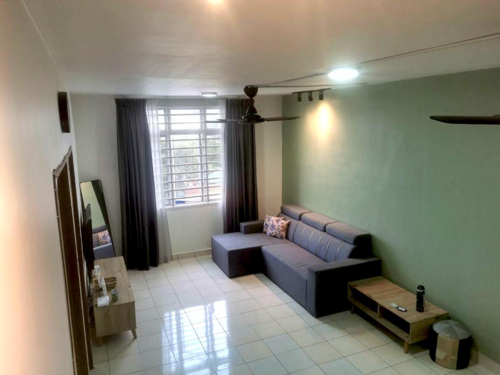 ein Wohnzimmer mit einem blauen Sofa und einem Fenster in der Unterkunft Putatan Platinum Apartment with Pool in Kota Kinabalu