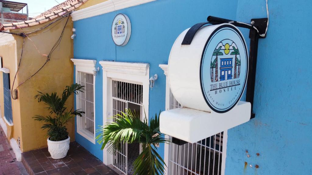 een bord aan de zijkant van een blauw gebouw bij The Blue House Hostel in Santa Marta