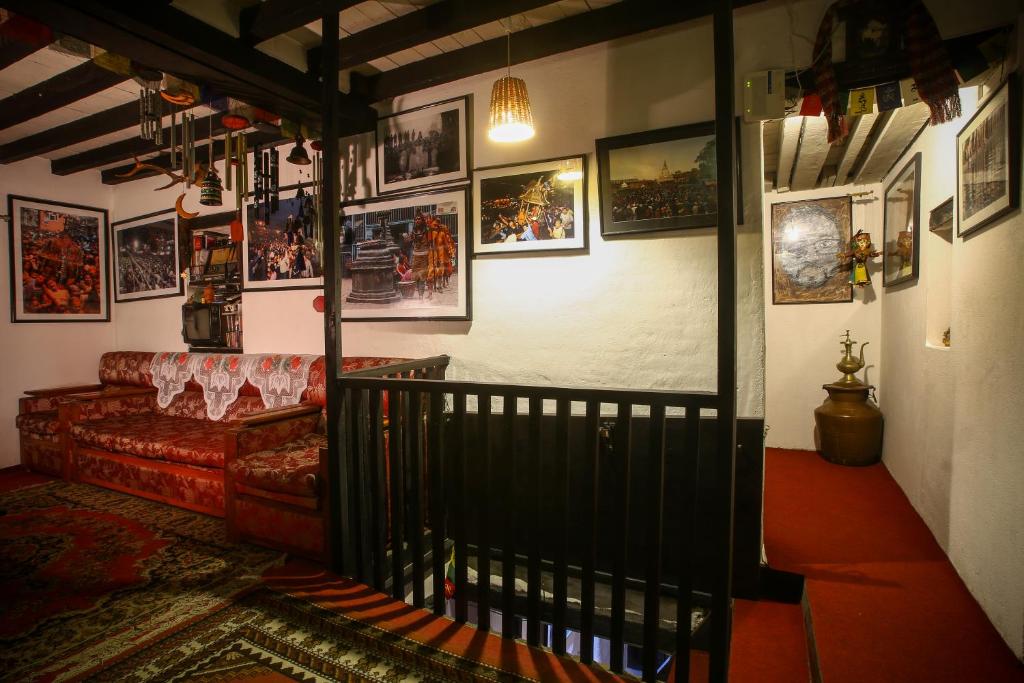 a living room with a couch and pictures on the wall at Traditional Newari Homestay in Pātan