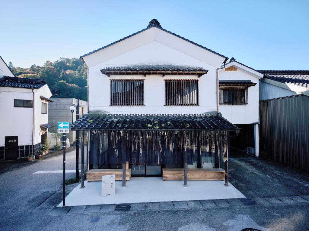 a white house with a black awning on a street at 小鳩屋 in Asuke-chō