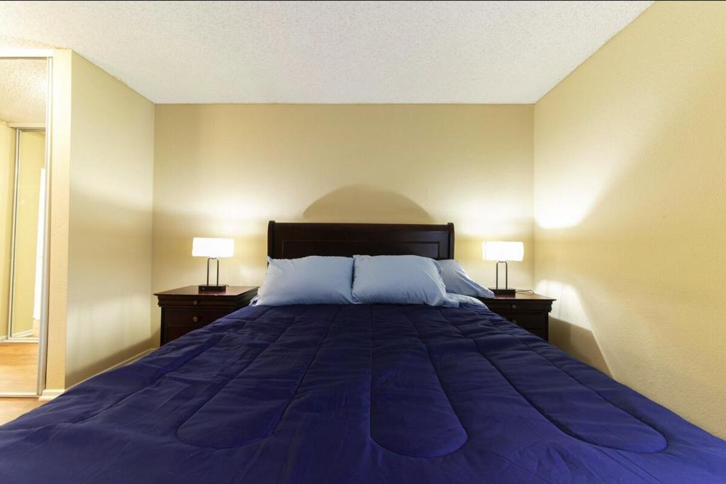 a bedroom with a large blue bed with two lamps at Luxurious stay near the beach in Newport Beach