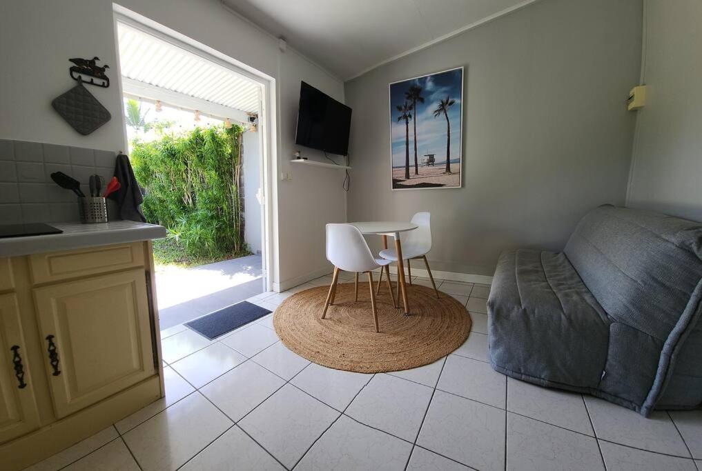 a kitchen and living room with a table and a couch at Bungalow climatisé à 200 m du lagon 2/3 pers in La Saline les Bains