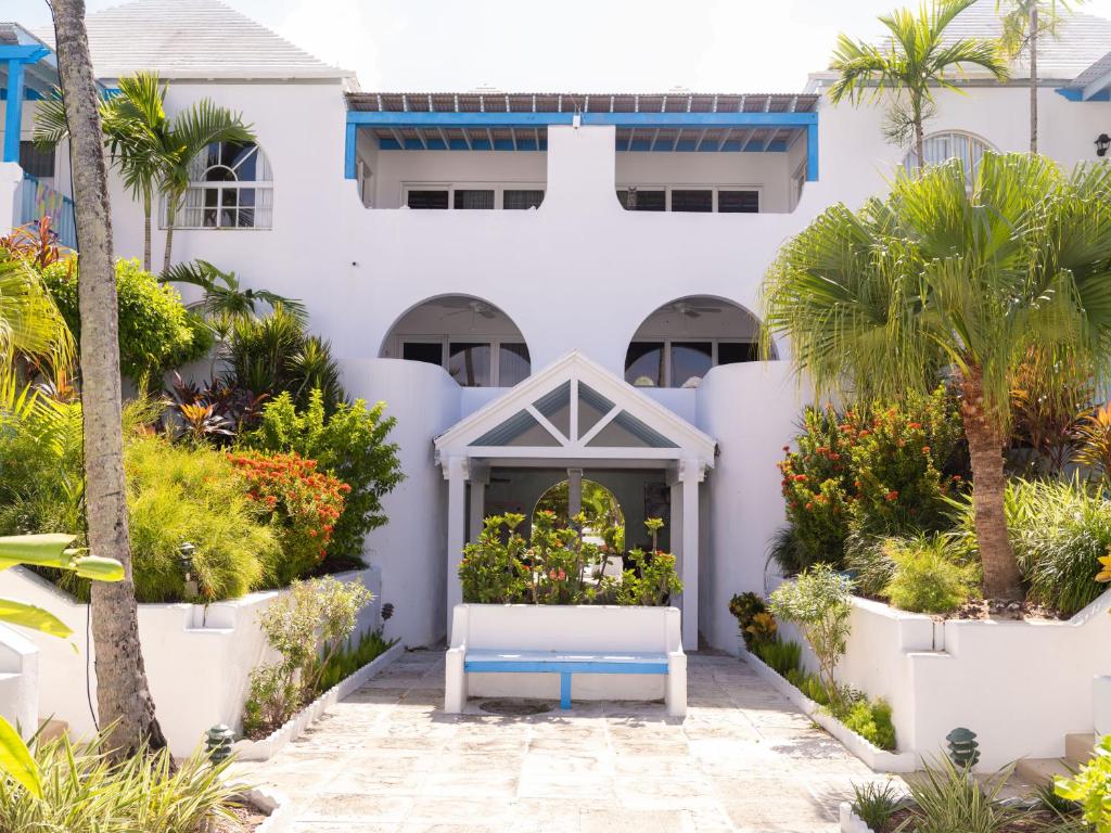 a white house with a blue bench in front of it at Garden View Villas at Paradise Island Beach Club in Creek Village