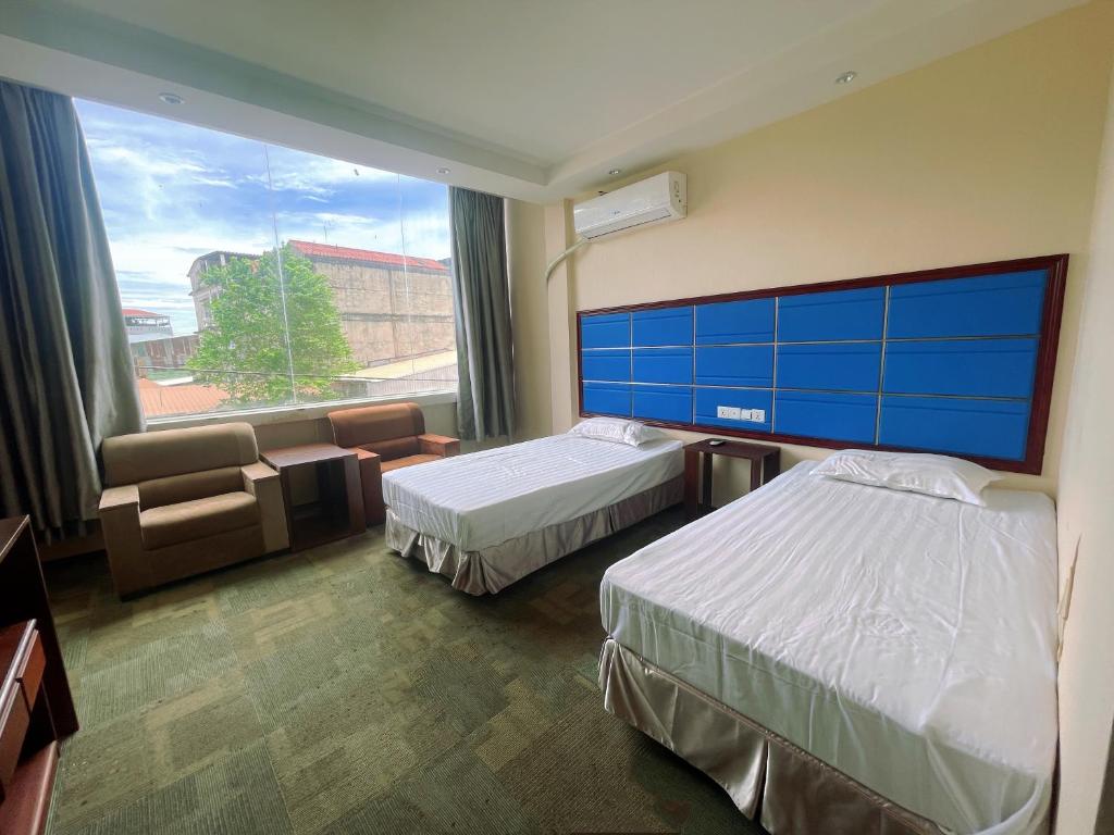 a hotel room with two beds and a large window at Thavixay Hotel in Vientiane