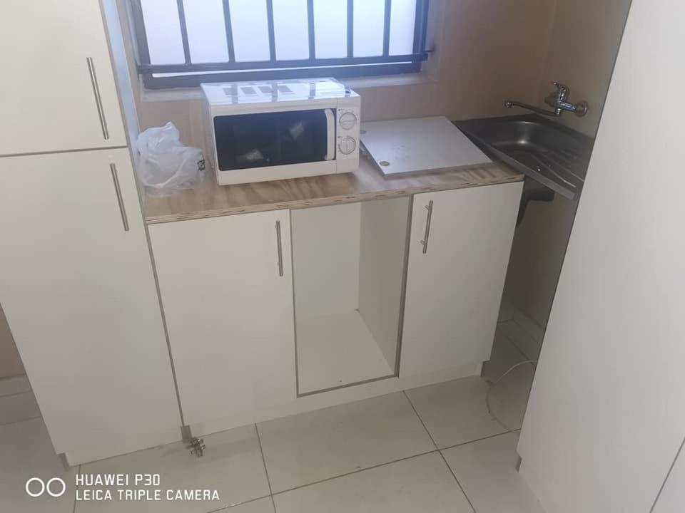 a kitchen with a counter with a microwave and a sink at Kpt property investment in Soweto