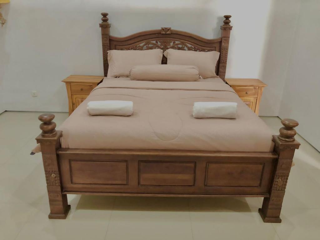 una cama de madera con 2 almohadas encima en Petak Homestay Ubud, en Penginyahan