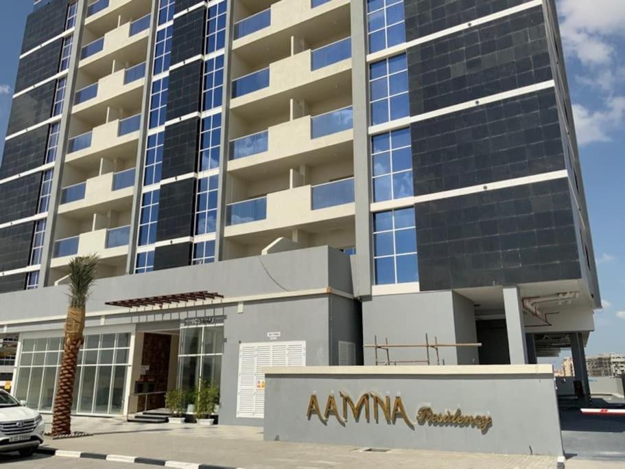 Un grand bâtiment avec un panneau d'aania devant lui dans l'établissement 2BR W Pool-20 min to DXB APT & Dubai Mall, à Dubaï