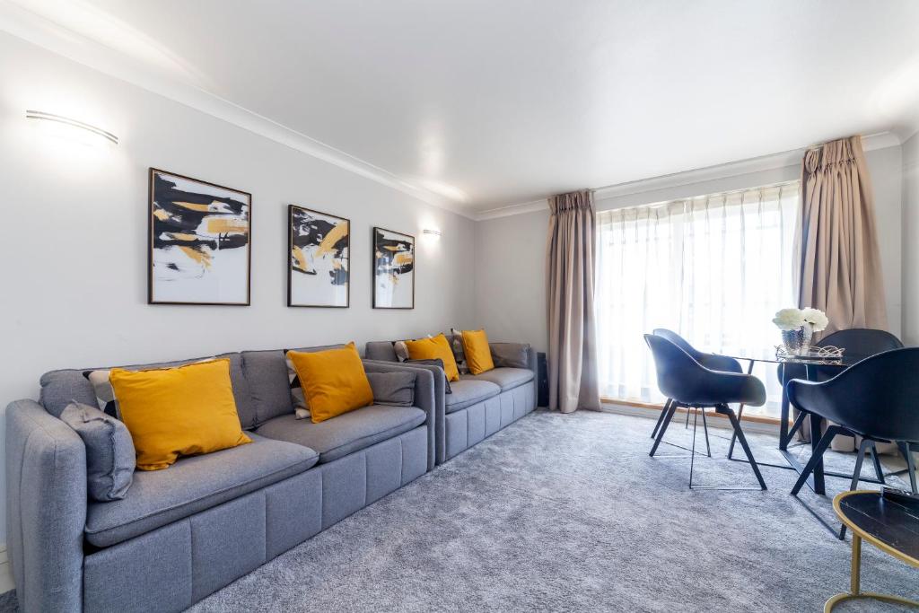 sala de estar con sofá gris y almohadas amarillas en Stylish 1 bedroom apartment in Maida Vale en Londres