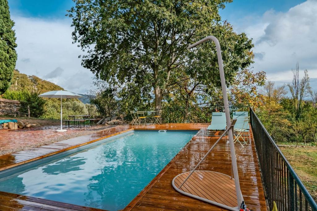 uma piscina com um deque de madeira e uma cerca de metal em Rectoría de Castellar em La Vall de Bianya