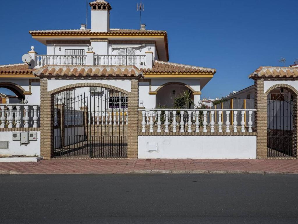 una casa blanca con una puerta y una valla en La Fonda de Julia Magnifica casa muy luminosa y amplia con chimenea y barbacoa, en Matalascañas