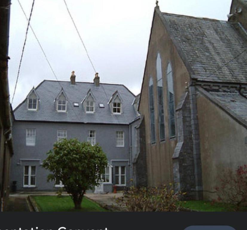 a large gray building next to a church at Presentation Convent in Mooncoin