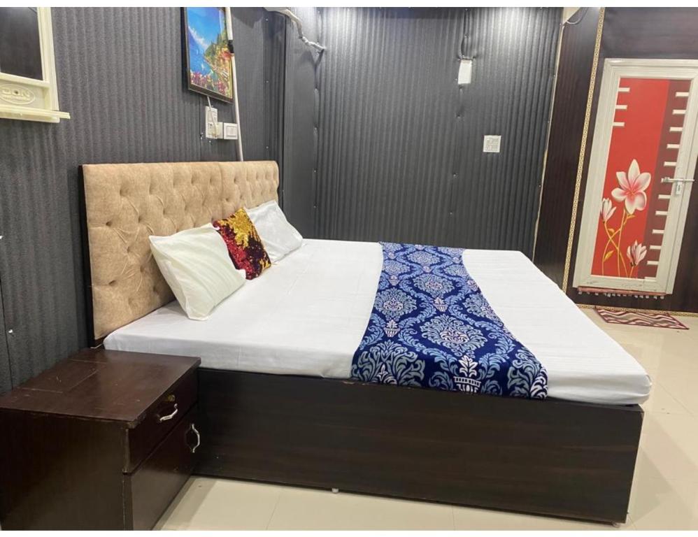 a bedroom with a bed with a blue and white blanket at Hotel Subh Ratri, Jhansi in Jhānsi