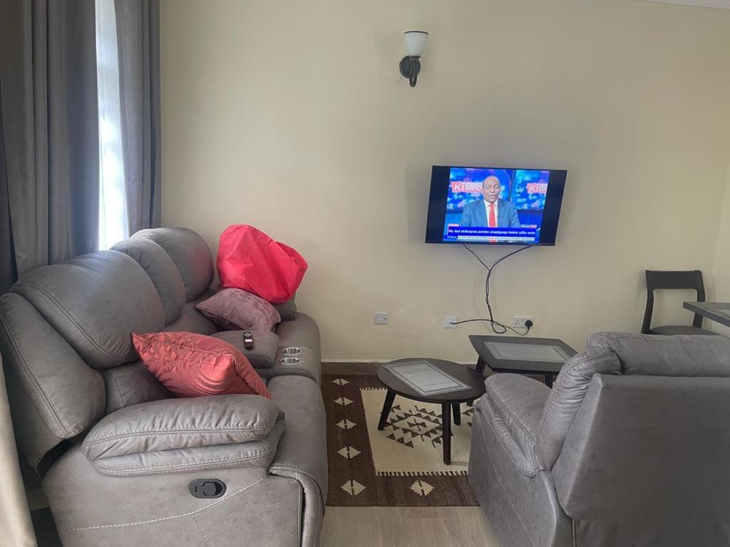 een woonkamer met een bank en een flatscreen-tv bij Lux Suites Narok Holiday Homes in Narok