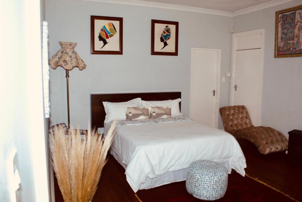 Un dormitorio con una cama blanca y una silla. en Cozy oasis on Derby, en Johannesburgo
