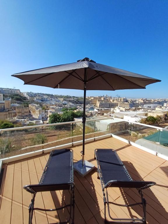 a pair of chairs and an umbrella on a roof at Is- Sienja in Kalkara