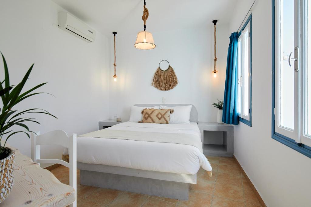 イメロヴィグリにあるAthiri Santorini Hotelの白いベッドルーム(ベッド1台、鉢植えの植物付)