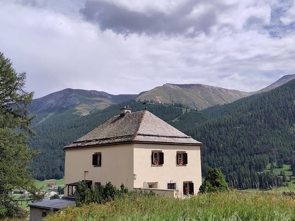 an old house on a hill with mountains in the background at Villa Bochert in Zuoz