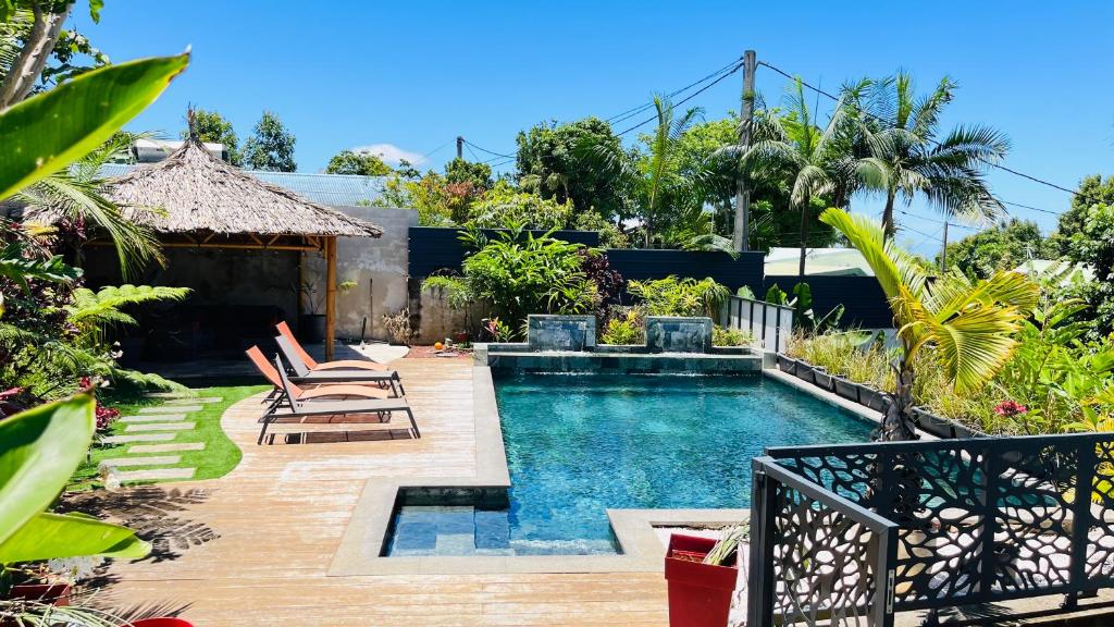 - une piscine dans une arrière-cour entourée de chaises dans l'établissement Charmant rez de jardin avec acces piscine, à Le Tampon