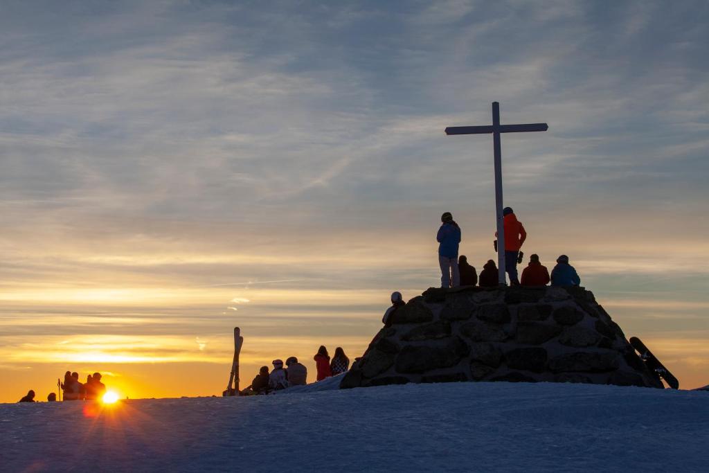 a group of people standing around a cross on a hill at Le Chamois in Chamrousse