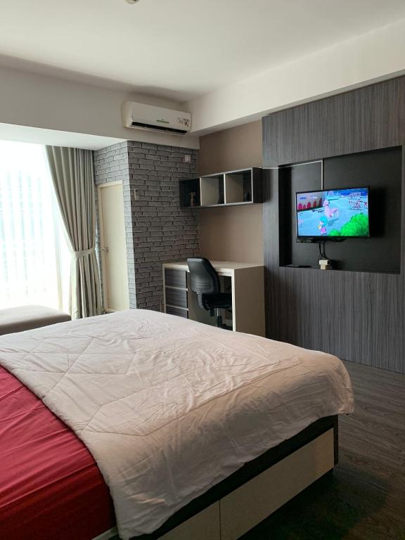 Cette chambre comprend un lit et une télévision à écran plat. dans l'établissement Vins Room at Mataram City Tower Sadewa, à Kejayan