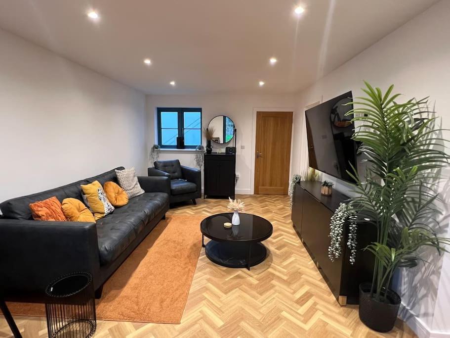 a living room with a black couch and a tv at The Orchard - Ground Floor Flat in Bristol
