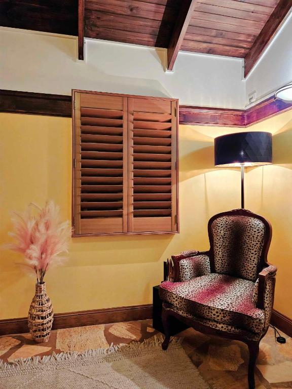 a room with a chair and a vase with a lamp at The Gamekeepers Spa Cottage in Tamborine Mountain in Mount Tamborine