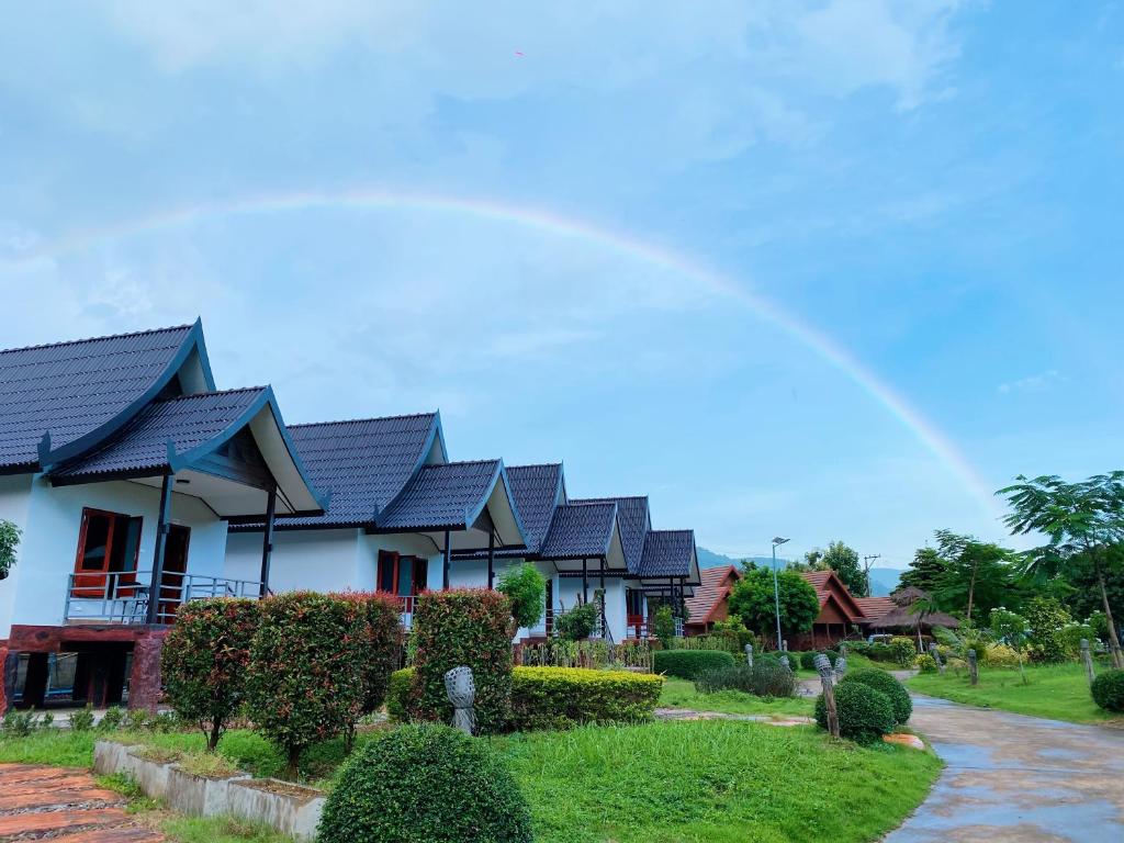 a row of houses with a rainbow in the background at Champathong Garden Resort in Vang Vieng