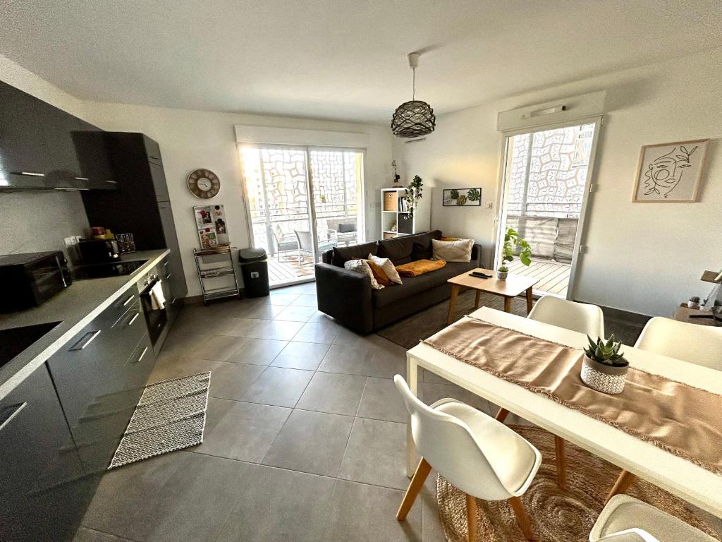cocina y sala de estar con sofá y mesa en Appartement cosy - Port Marianne - Garage sous sol, en Montpellier