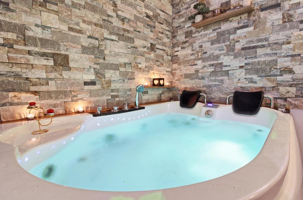 a large bath tub in a room with a stone wall at Aux 3 Glands - Nature & Spa in Dieffenbach-au-Val