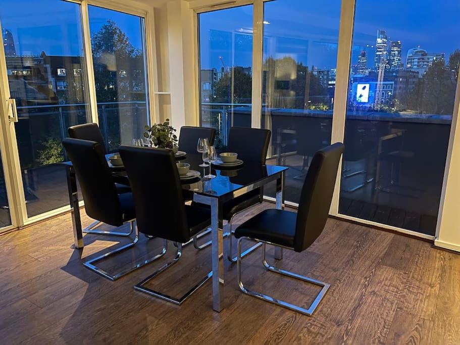 une salle à manger avec une table et des chaises noires dans l'établissement Sky View by condokeeper, à Londres